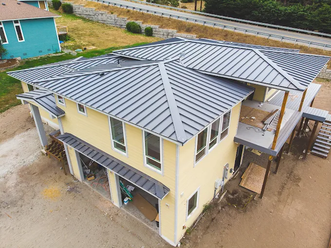 Hillside home with a new dark standing-seam metal roof and wrap-around porch